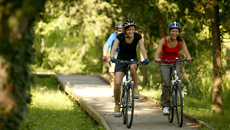 Ragazze sorridenti pedalano in un parco cittadino in sella a biciclette