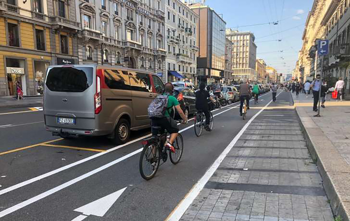Una fila di ciclisti urbani pedalano sulla ciclabile a fianco della carreggiata