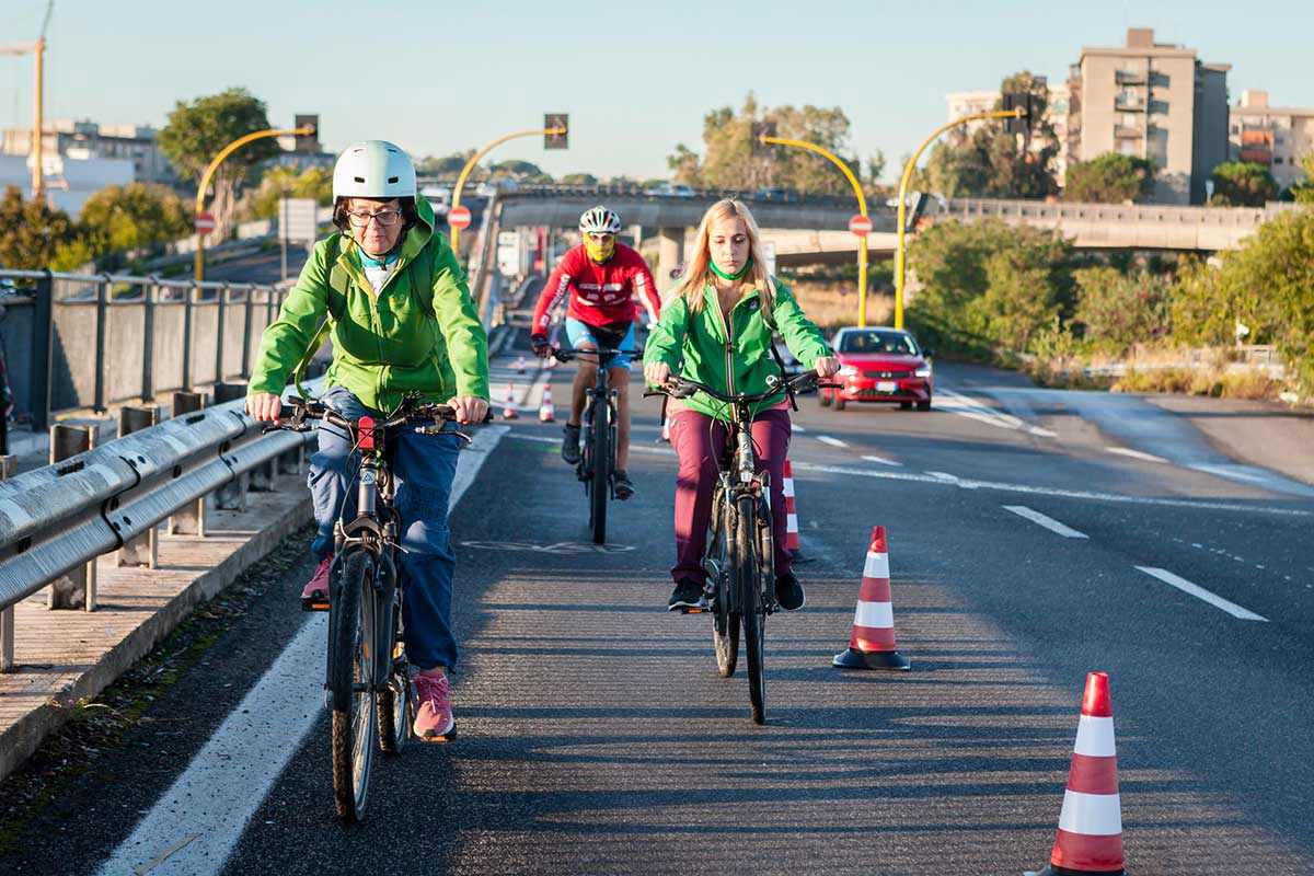 Una famiglia pedala sulla pista ciclabile parallela alla strada