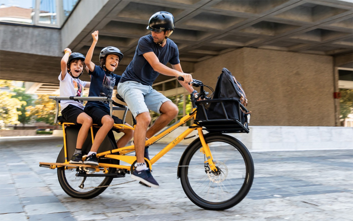Un uomo trasporta i suoi figli sulla bici cargo