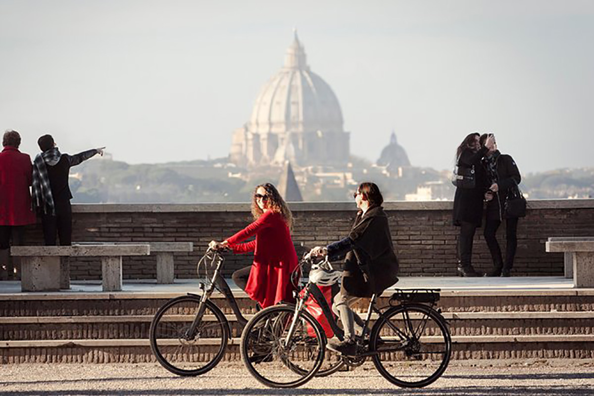 Due donne pedalano per la città in sella alle loro bici elettriche