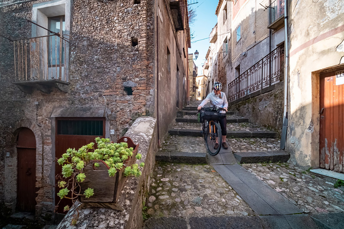 Una ciclista visita un borgo ubicato nella Ciclovia dei Parchi della Calabria