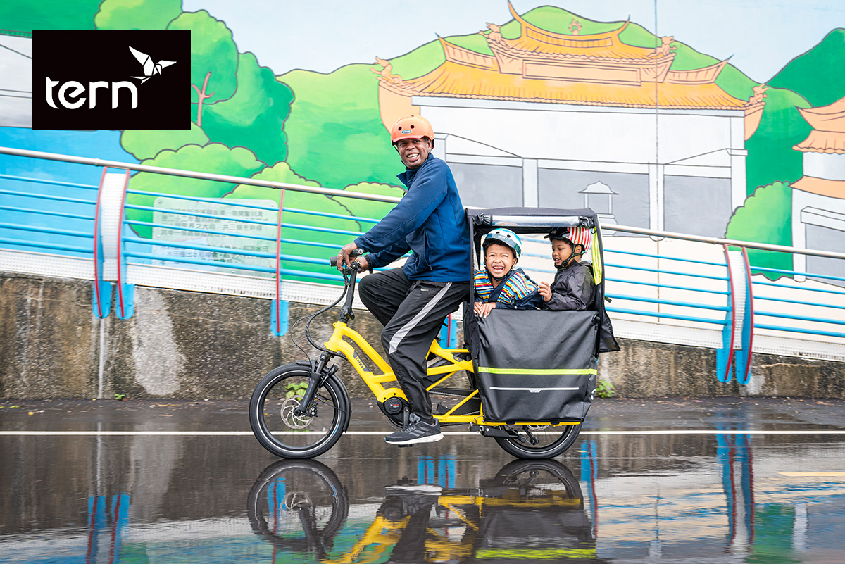 Un padre trasporta i suoi figli su una cargo bike Tern