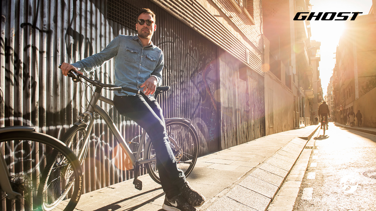 Un uomo sul marciapiede con la sua nuova bici urbana Ghost Square Trekking 2022