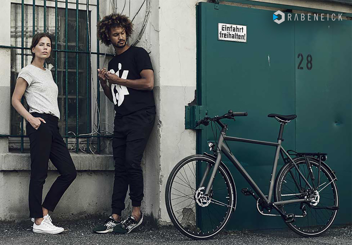 Una coppia in strada di fianco ad una nuova bicicletta Rabeneick urbana 2022