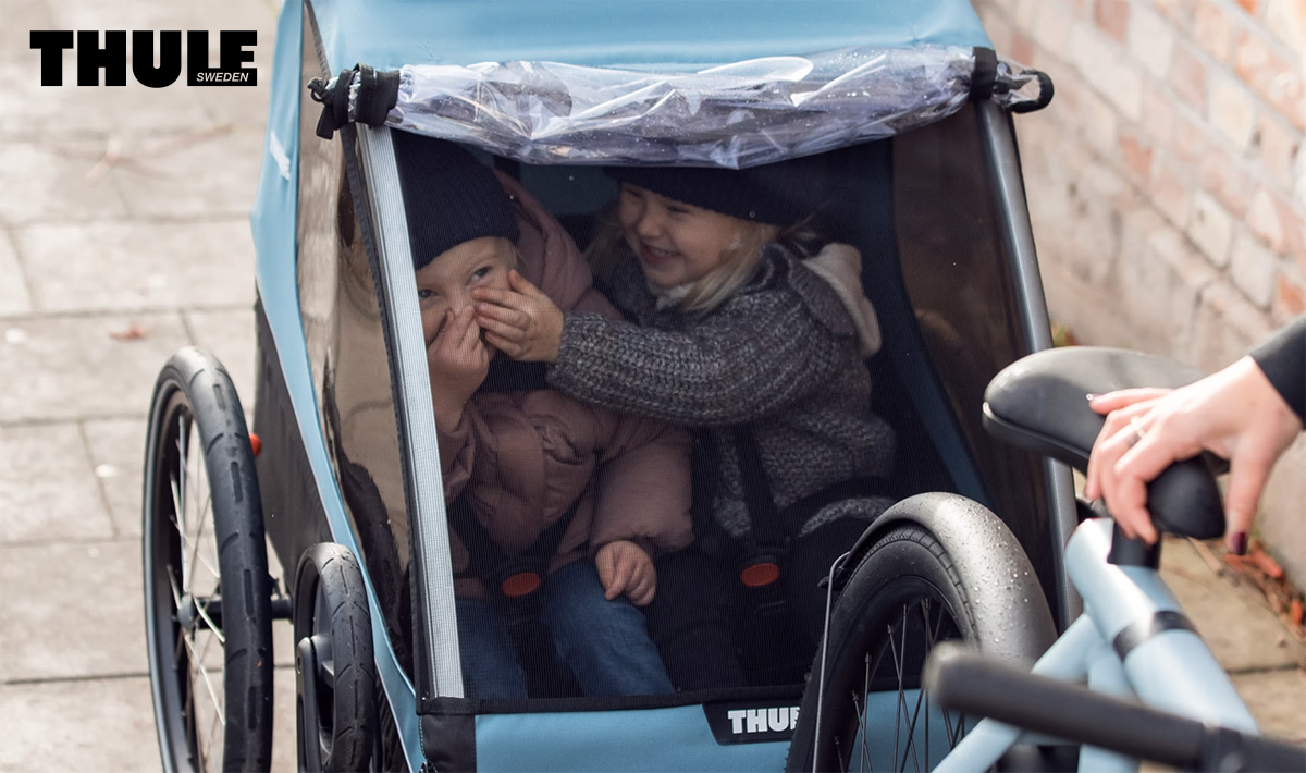 Dei bambini seduti dentro al nuovo carrellino per bici Thule Courier 2022