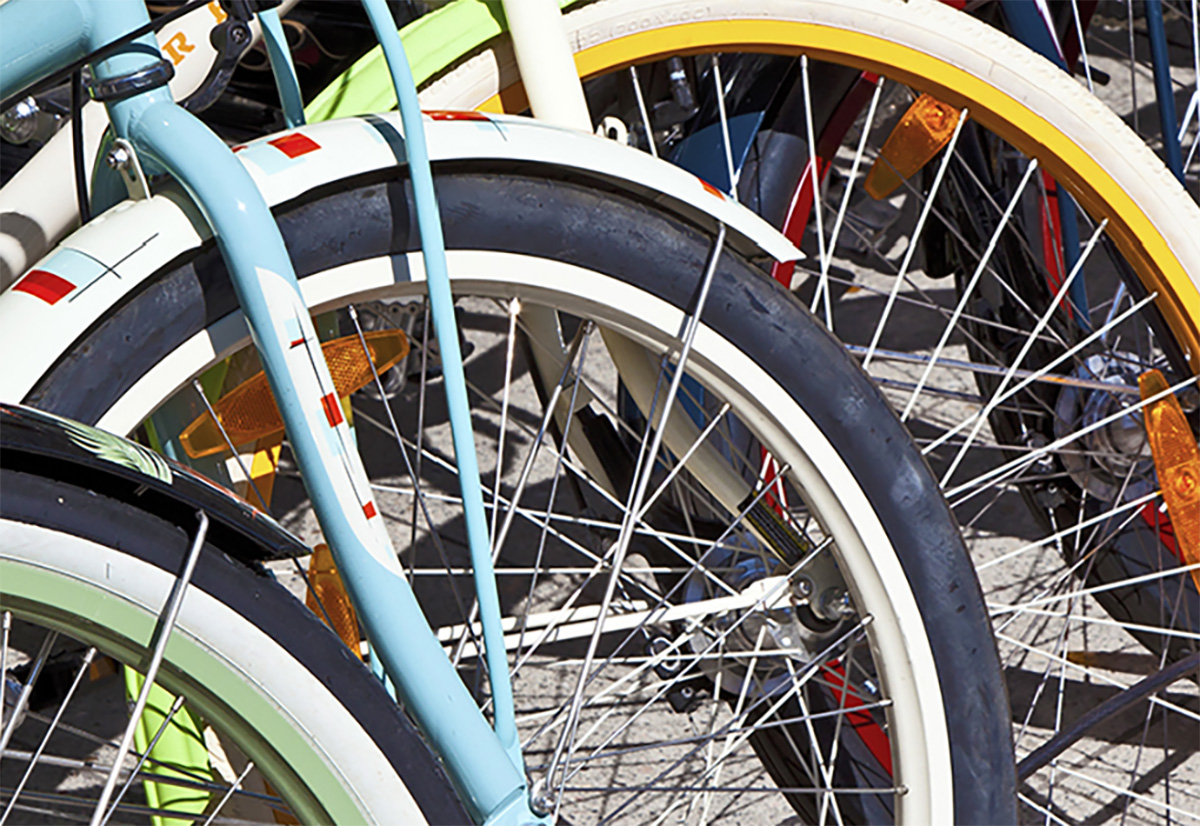 Dettaglio delle ruote anteriore di alcune biciclette parcheggiate vicine