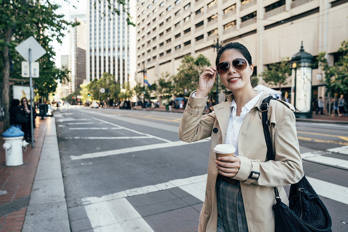 Una donna beve il caffè e cammina verso l'ufficio in città