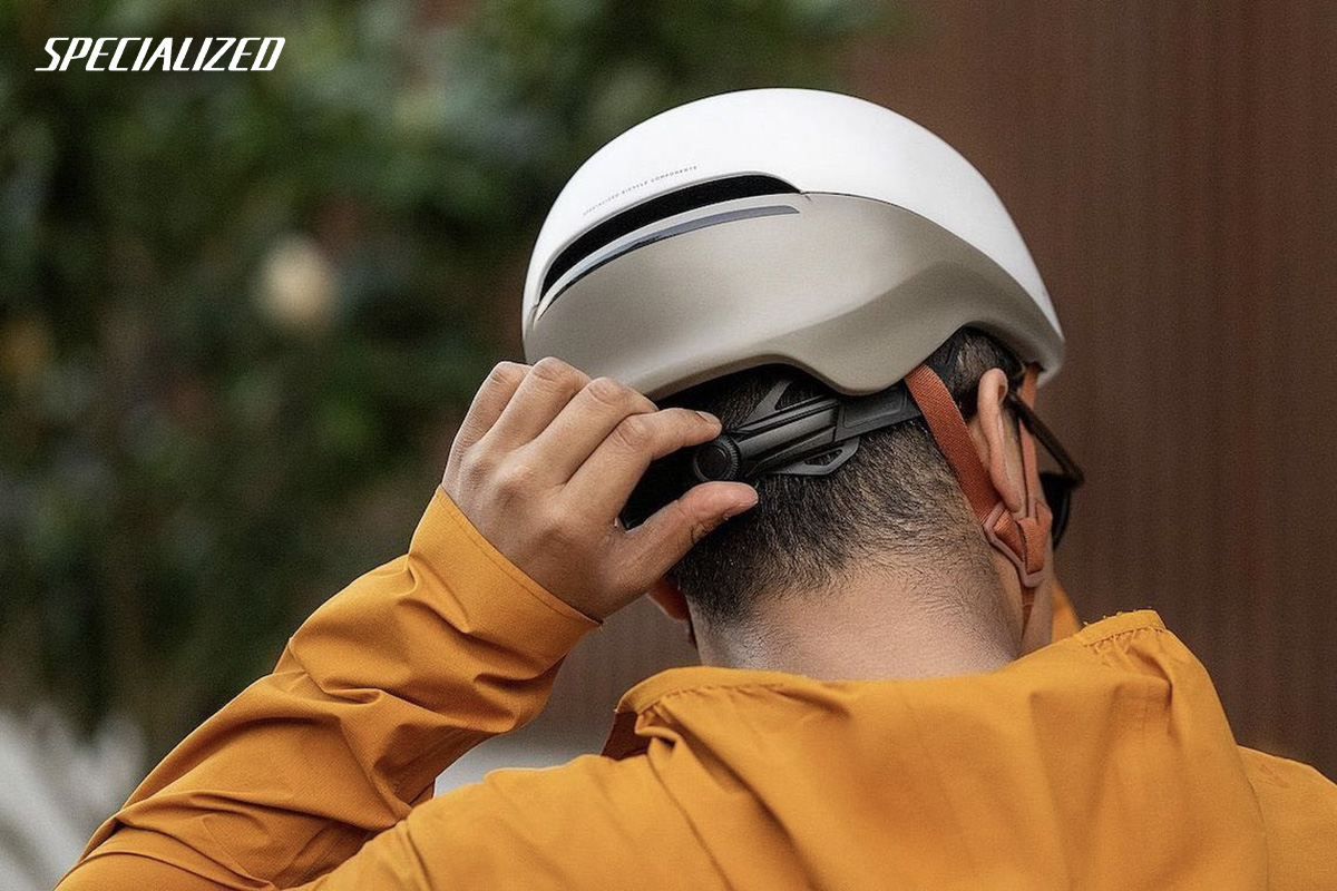 Un uomo si regola il nuovo casco per biciclette da città Specialized Tone 2023 con sistema MIPS 