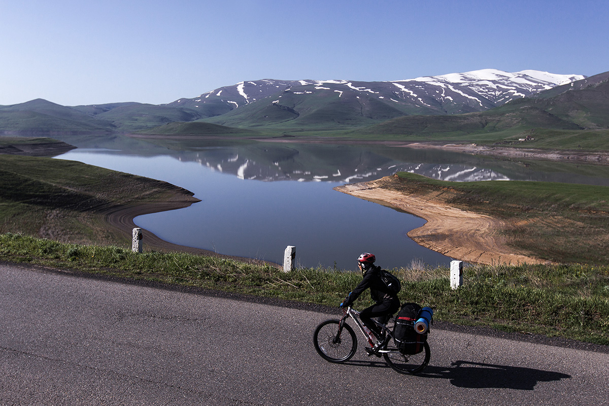Un cicloturista pedala su una strada con vista lago