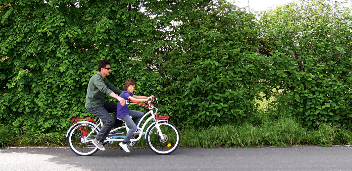 Un adulto e un bambino pedalano su un tandem Hugbike